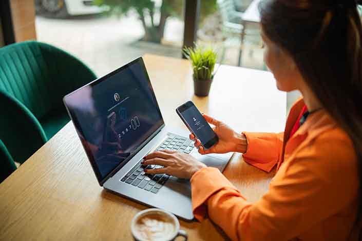 person looking at cell phone and typing on computer