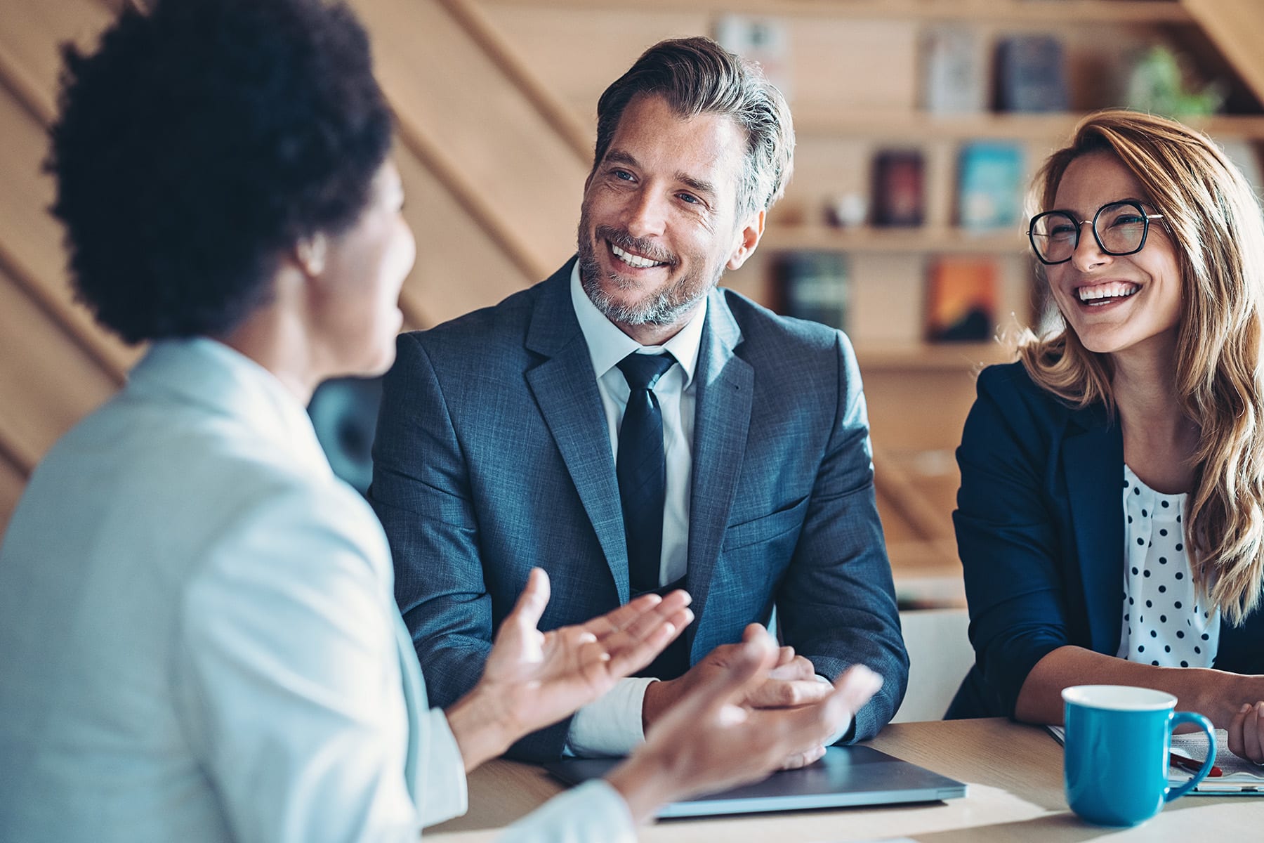 three business professionals sitting at a table having a conversation