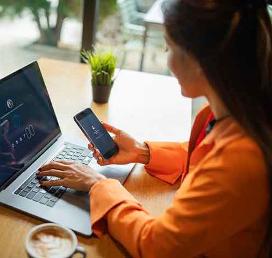 person looking at cell phone and typing on computer
