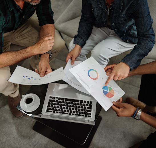 3 individuals looking and pointing at a piece of paper that has graphs on it