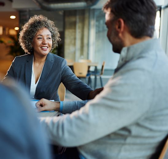 Woman in a suit speaking with a business owner about an SBA business acquisition loan