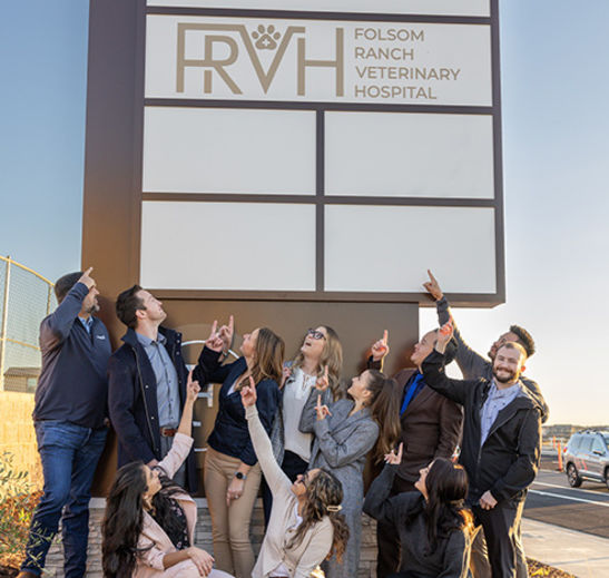 People pointing to a Folsom Ranch Veterinary Hospital sign outside