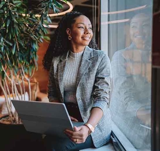 person sitting with laptop and looking out a window