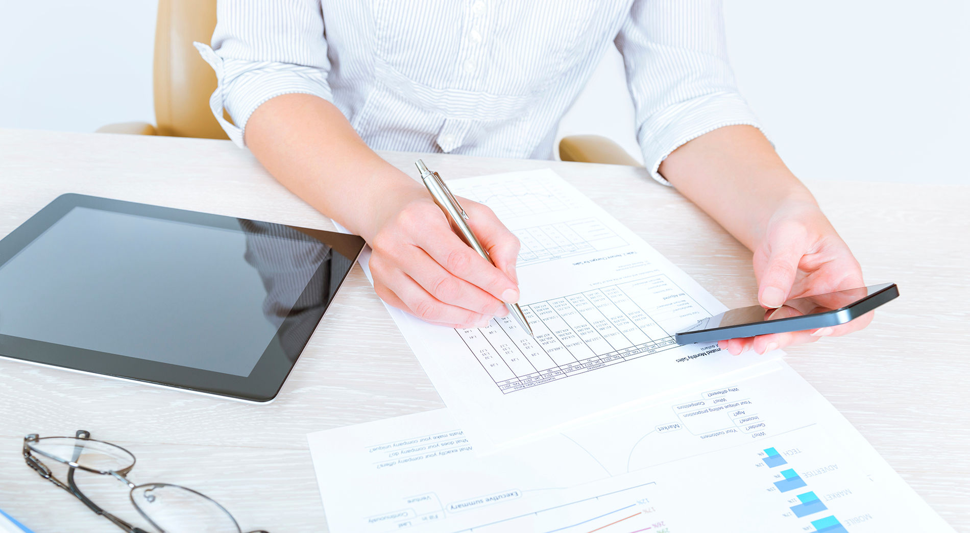 A woman reviewing paperwork and doing research on SBA 7a loan requirements