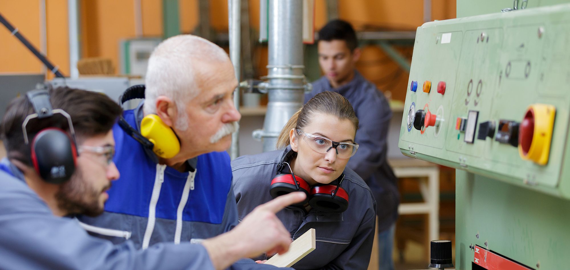 3 workers looking at a CNC machine
