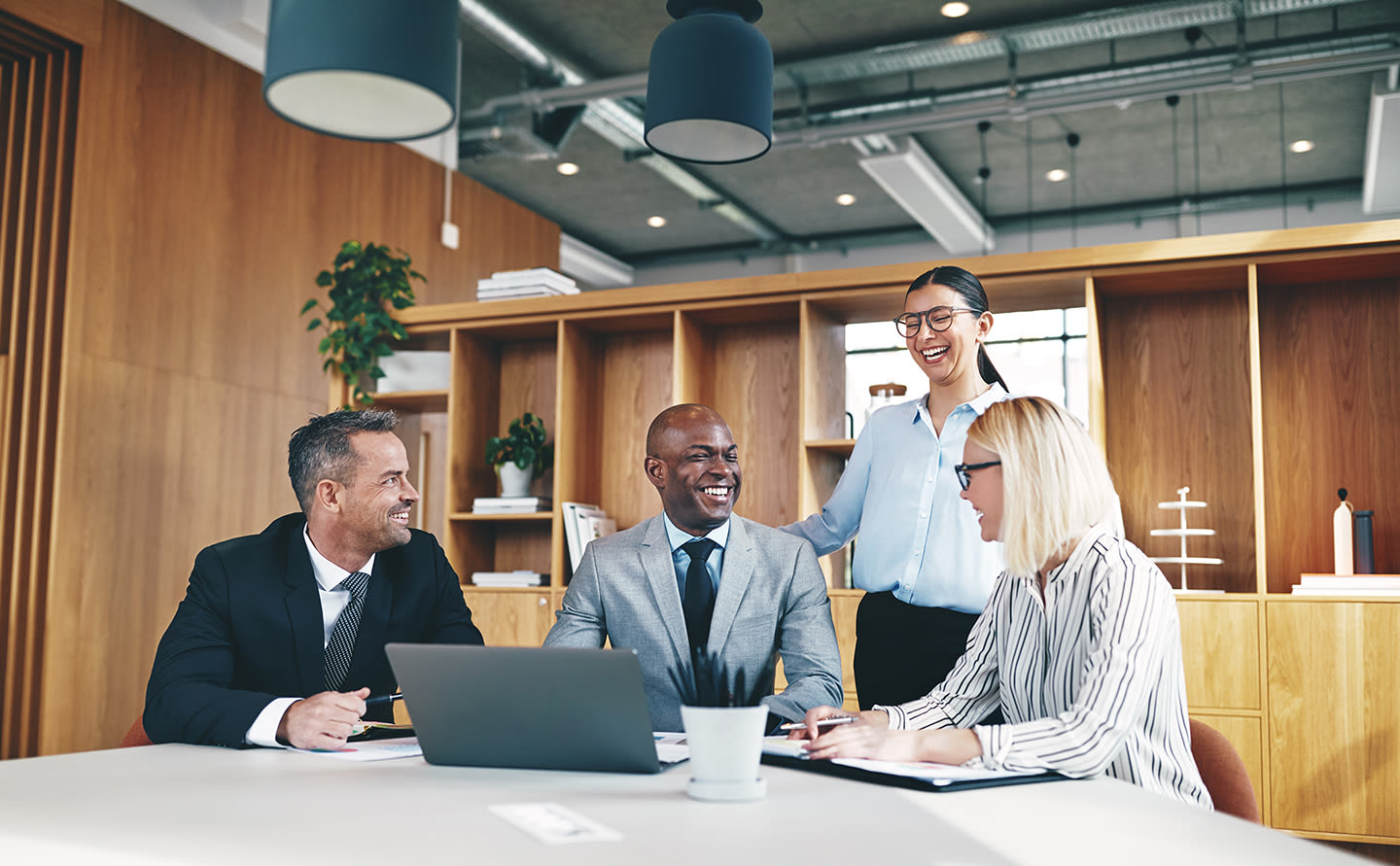 4 workers gathered around a table and are smiling and laughing