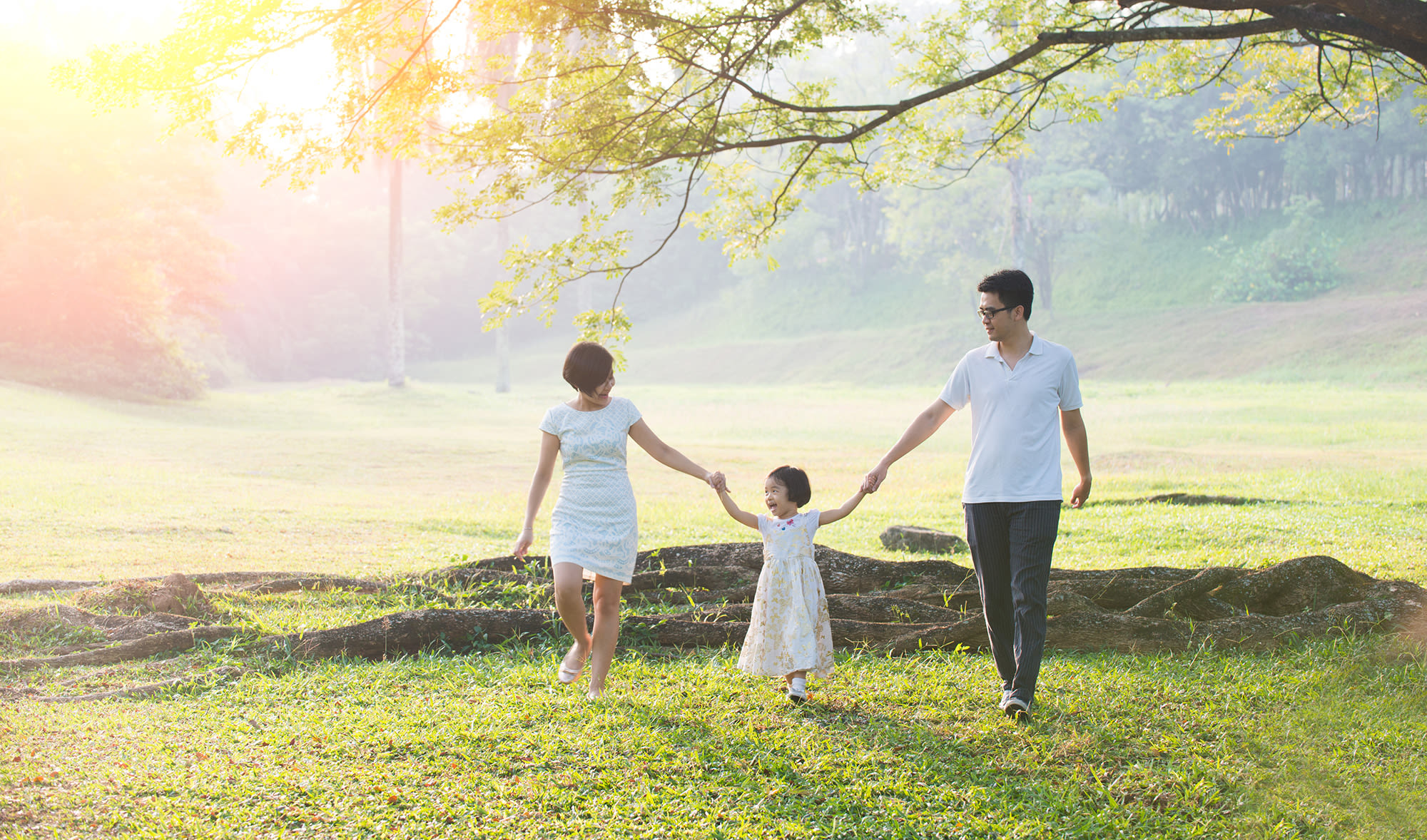 family walking through the grass holding hands