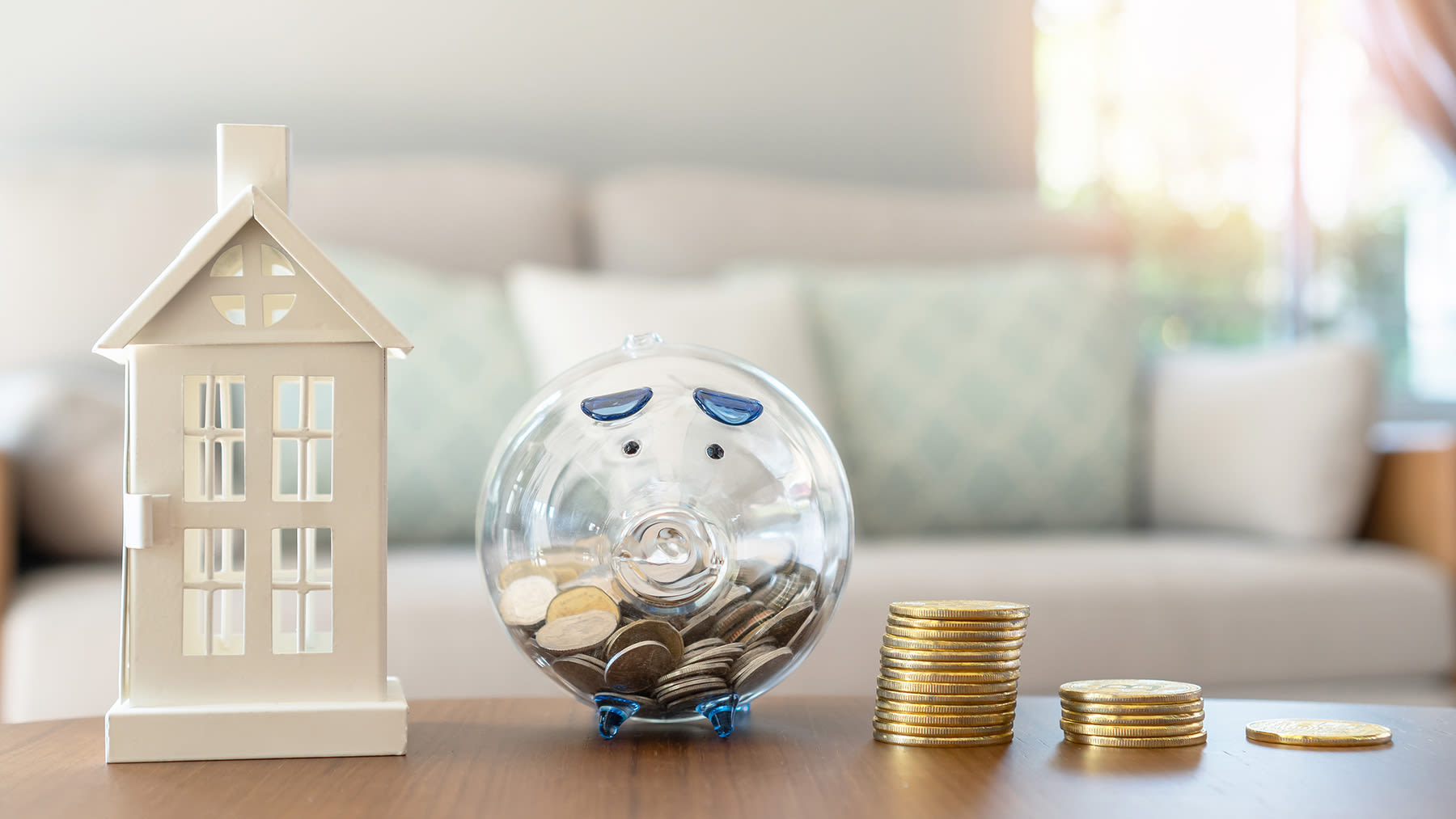 piggy bank with small house and coins sitting on a table