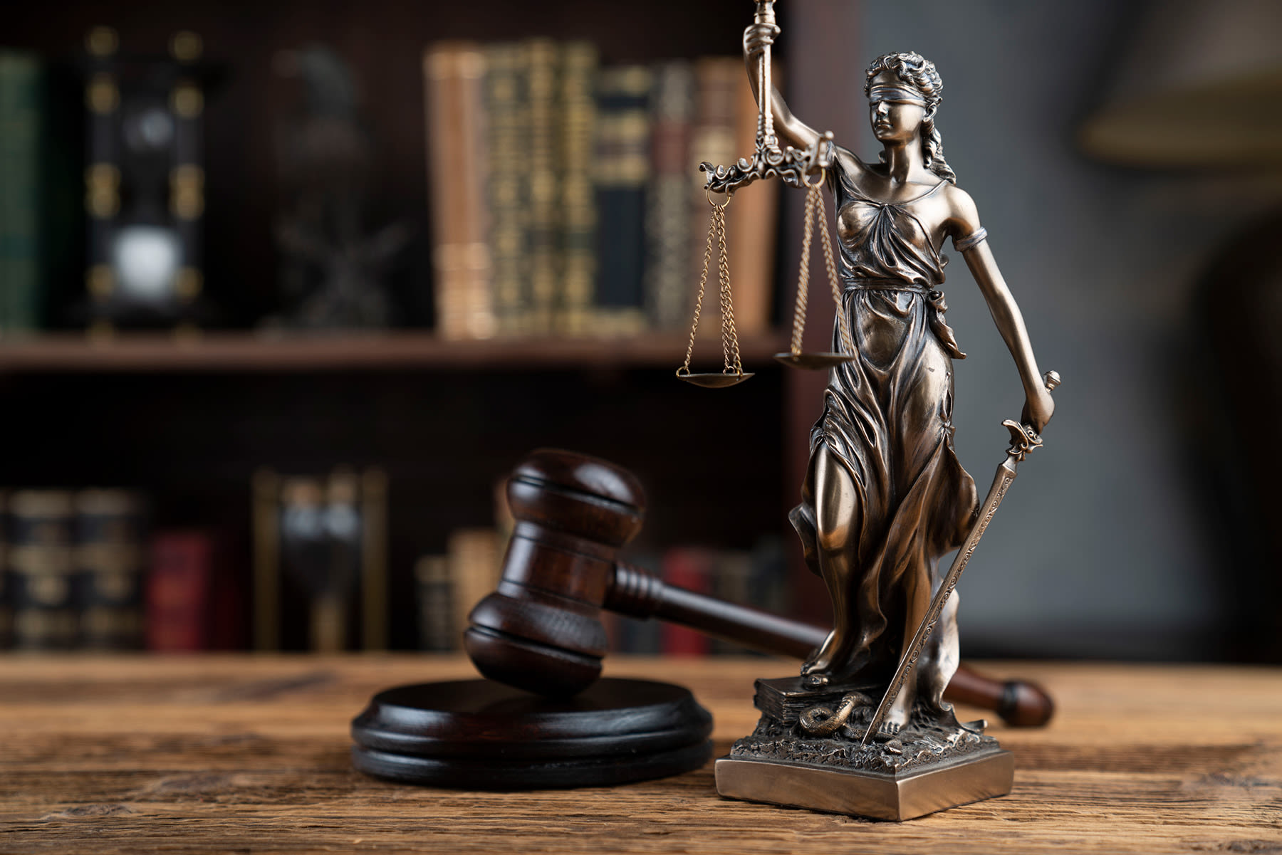 Lady Justice statue with gavel on a legal desk.