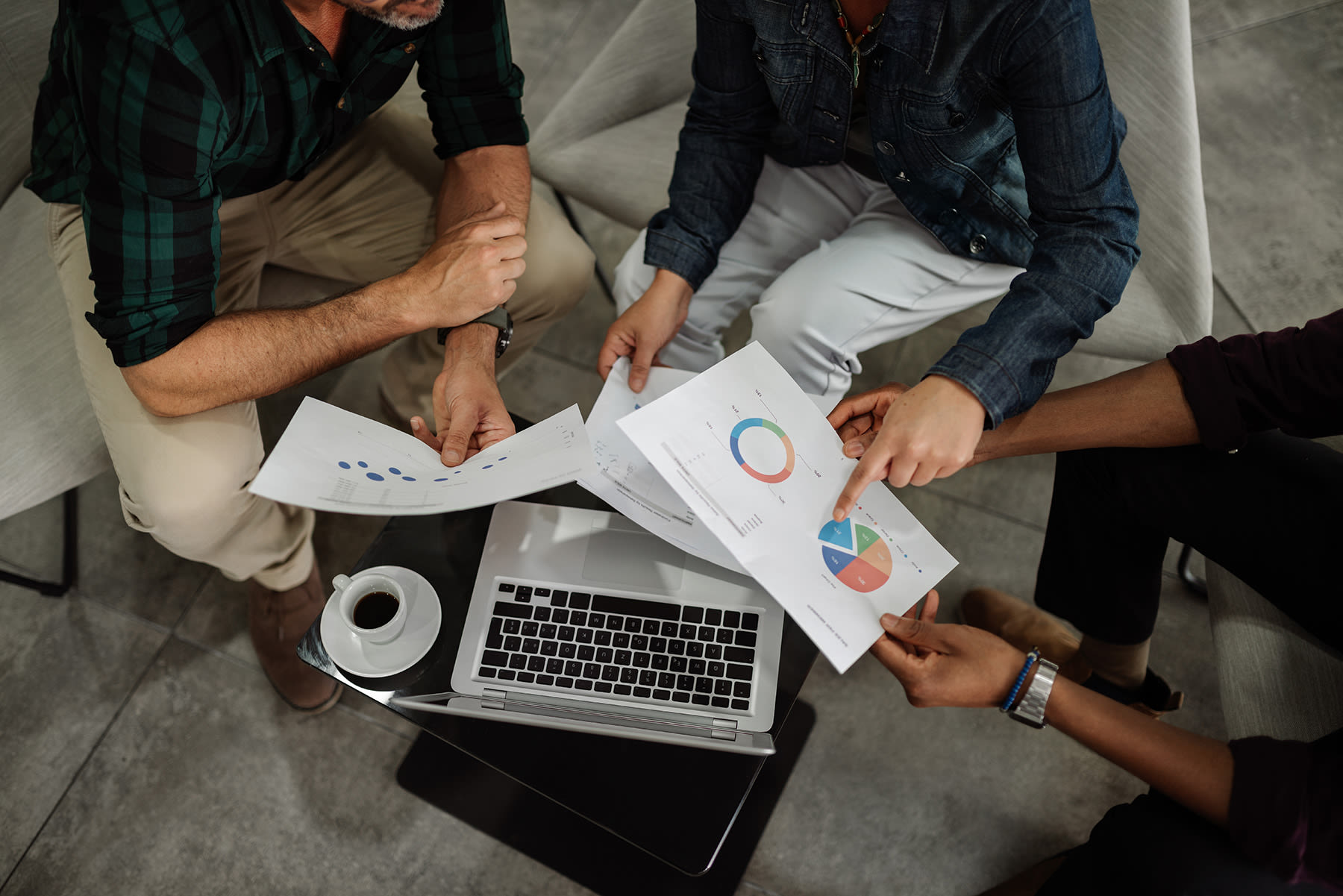Three people meeting looking at graphics and information on a laptop