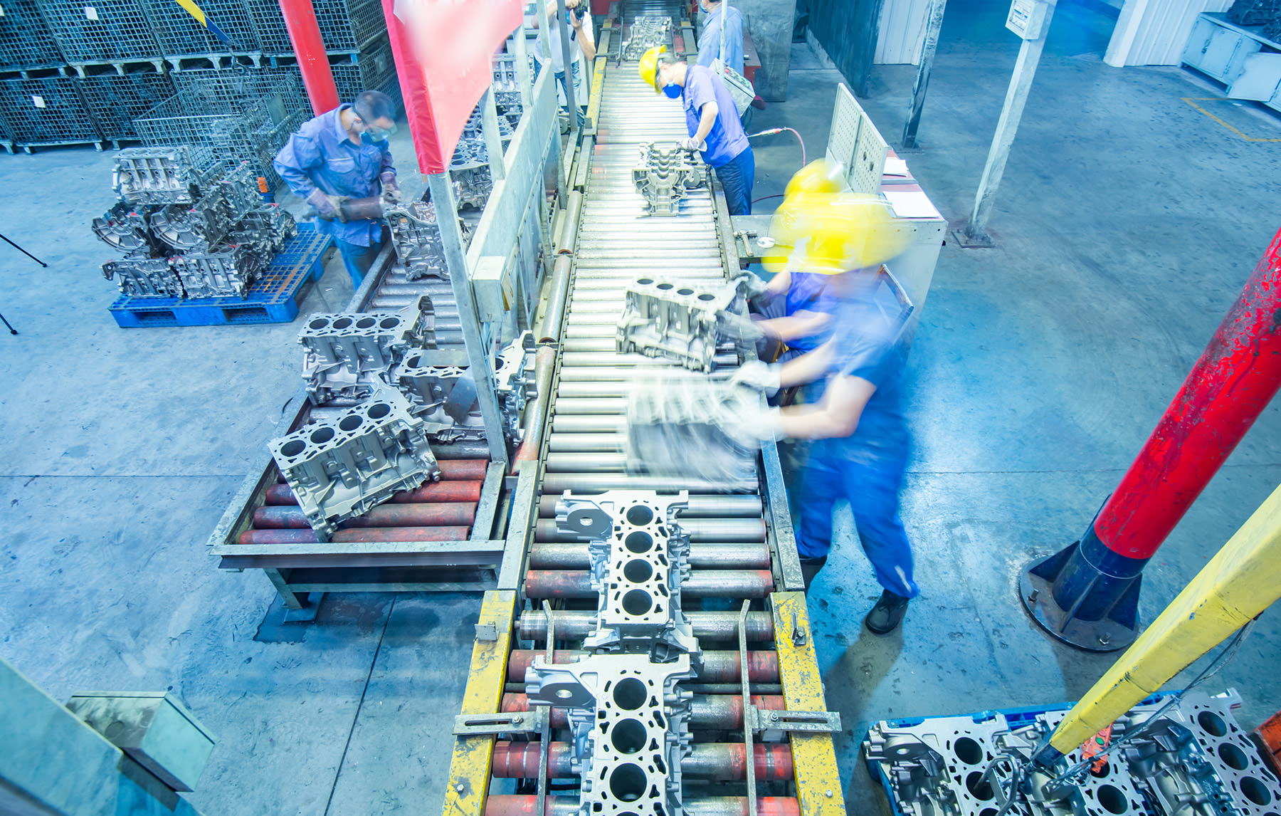Manufacturing production line with industrial equipment and workers assembling engine components, representing a business supported by asset-based lending during ownership or operational transitions.