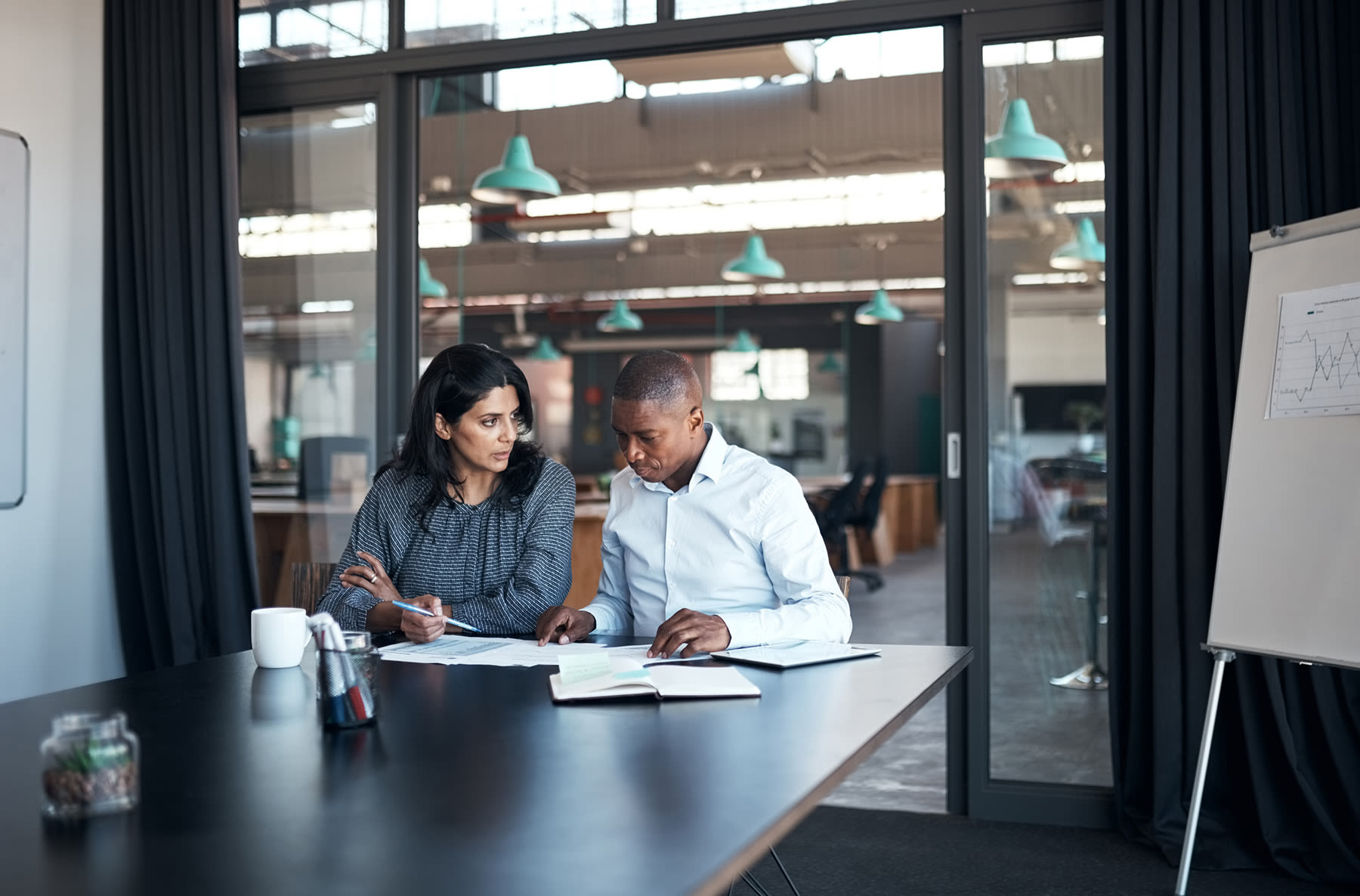 two people in a conference room discussing what to consider when a bank gets acquired