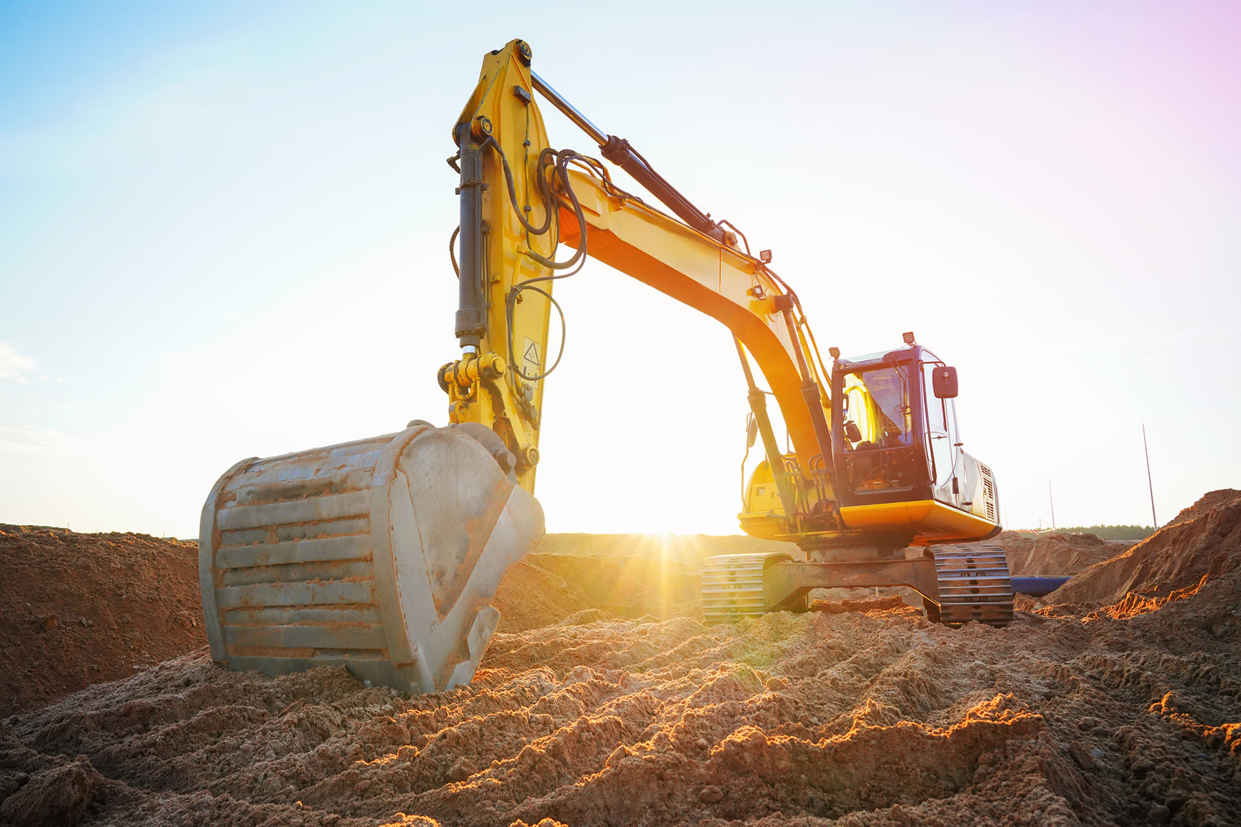 construction digging machine with a sunset behind it