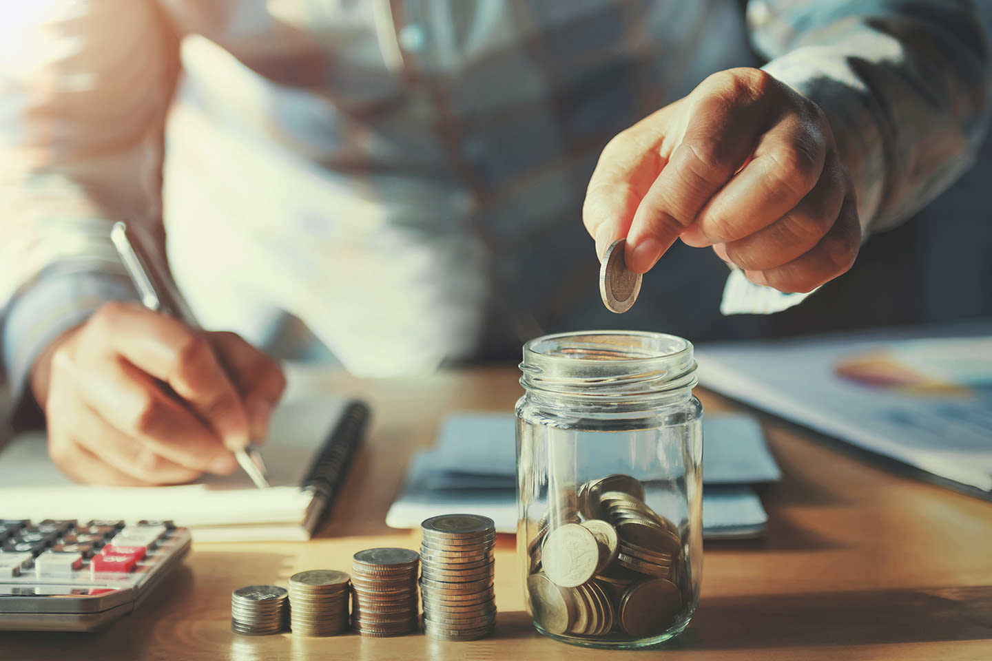 person putting a coin into a savings jar