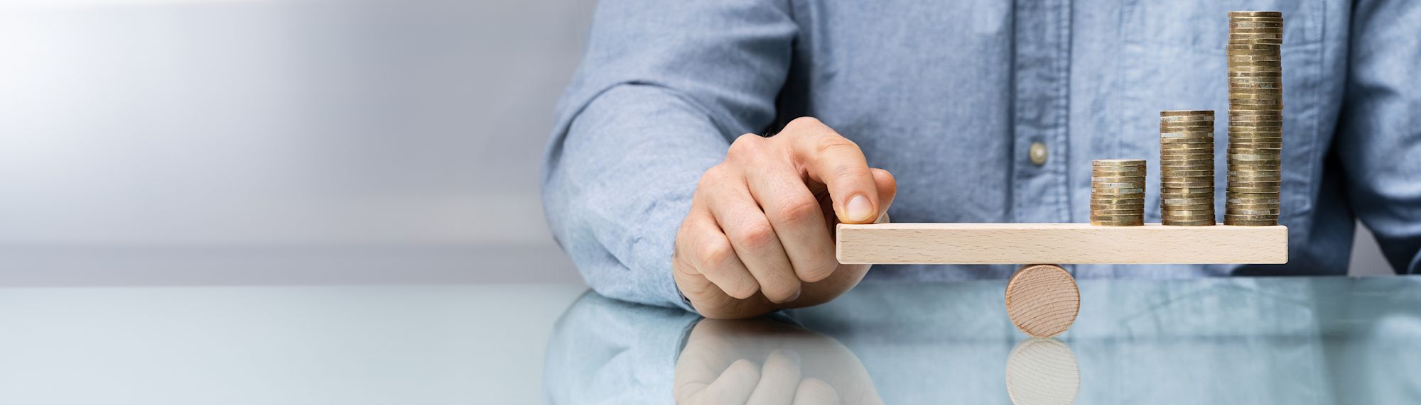 a person balancing coins on a small teeter totter