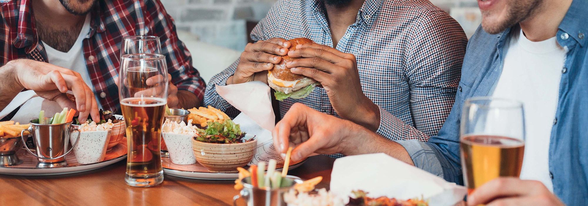 3 guys eating burgers and drinking beer