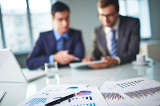 Two businessmen looking at documents and discussing them