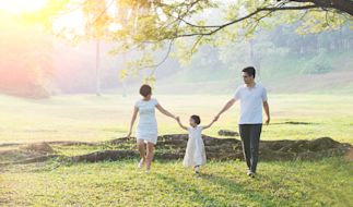 family walking through the grass holding hands