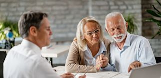 happy senior couple using computer while having a meeting with real estate agent