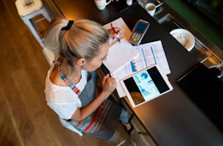 person working at a countertop looking at a tablet and papers with charts on them