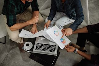 Three people meeting looking at graphics and information on a laptop
