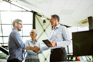 Business professionals shaking hands in a modern office, with a tablet visible, symbolizing partnership and collaboration.