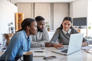 a couple meeting with a financial planner and looking at a laptop