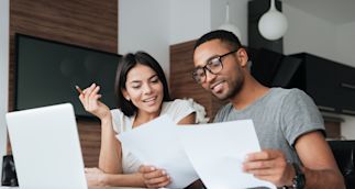 Two young individuals smiling and looking over retirement planning documents