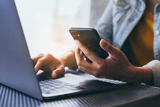 a person working on a phone and computer