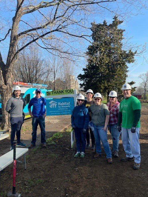 A team of First Business Bank’s Kansas City Metro employees with construction hats posing for a photo.