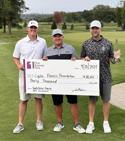 Three people holding a large $30,000 check written out to Cystic Fibrosis Foundation