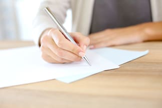 a person writing on a piece of paper on a desk