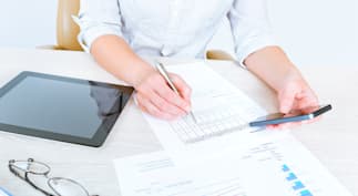 A woman reviewing paperwork and doing research on SBA 7a loan requirements