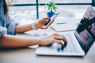 person using a phone and laptop at the same time