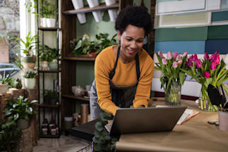 a person in a flower shop working on a laptop