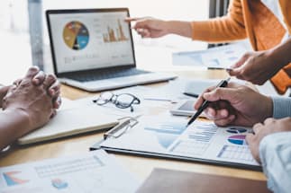 three people working together at a table looking at charts and graphs