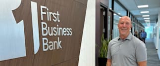 Employee Scott Crist Standing next to a First Business Bank sign